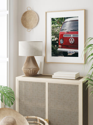 VW Bus photography print hanging in coastal living room. Red VW Bus photo print in Southern California. “Sea Rose Bus” photo print of a beautiful vintage VW Bus parked next to white wea roses in California by Kristen M. Brown of Samba to the Sea for The Sunset Shop. 