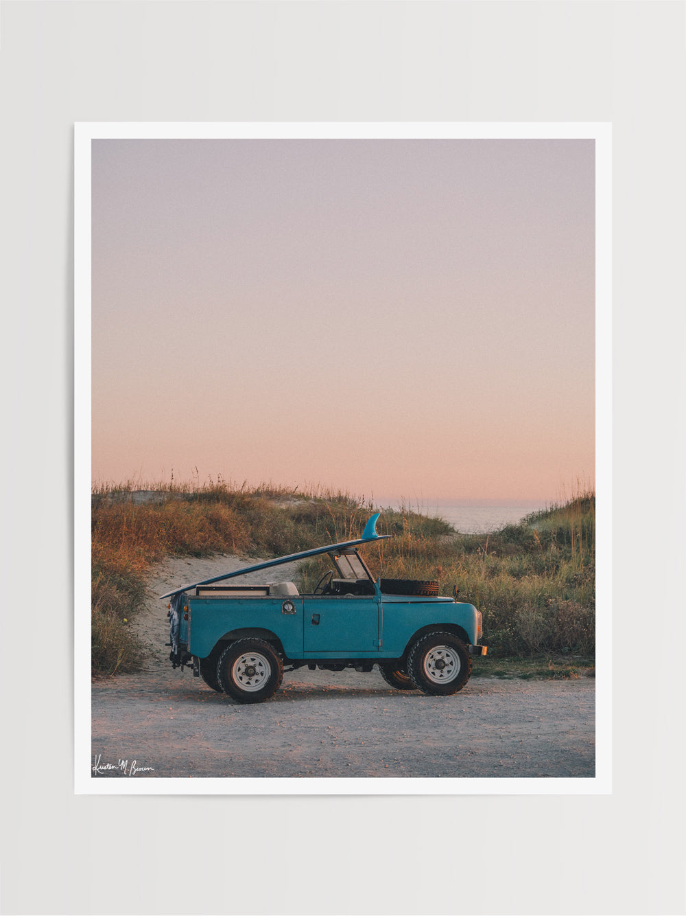 Photograph print of vintage Land Rover series truck parked at the beach with a classic single fin surfboard amidst a pastel pink sunset sky. "Wave Chaser" photographed by Kristen M. Brown, Samba to the Sea.