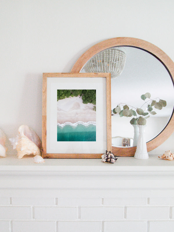 Aerial image of white sand beach and turquoise water of the beach at Playa Conchal, Costa Rica. Aerial beach print by Samba to the Sea at The Sunset Shop. Coastal living framed aerial beach print shelfie on white fireplace mantle.