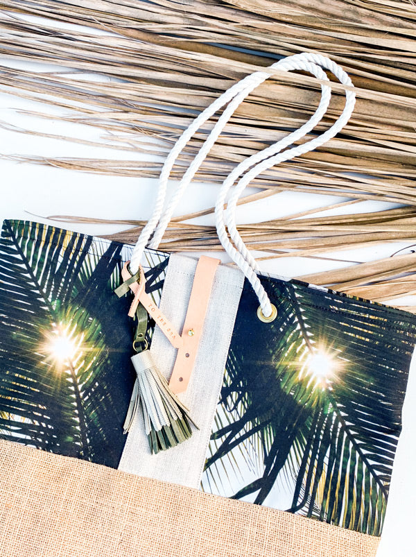 "Dreaming Under A Palm Tree" beach bag is the perfect bag to help you bring a piece of your tropical happy place with you, no matter where you may live. Palm tree print beach bag with leather tassels and cotton sailor rope. Chapman at Sea x Samba to the Sea collaboration.