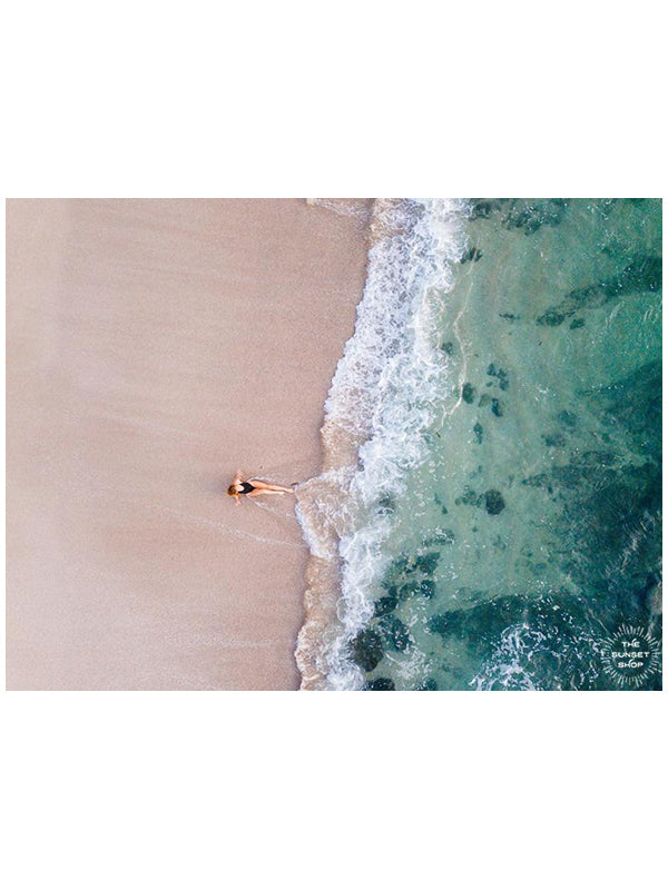 Woman laying on the beach as the waves reach her feet in Costa Rica. Photographed by Samba to the Sea for The Sunset Shop.