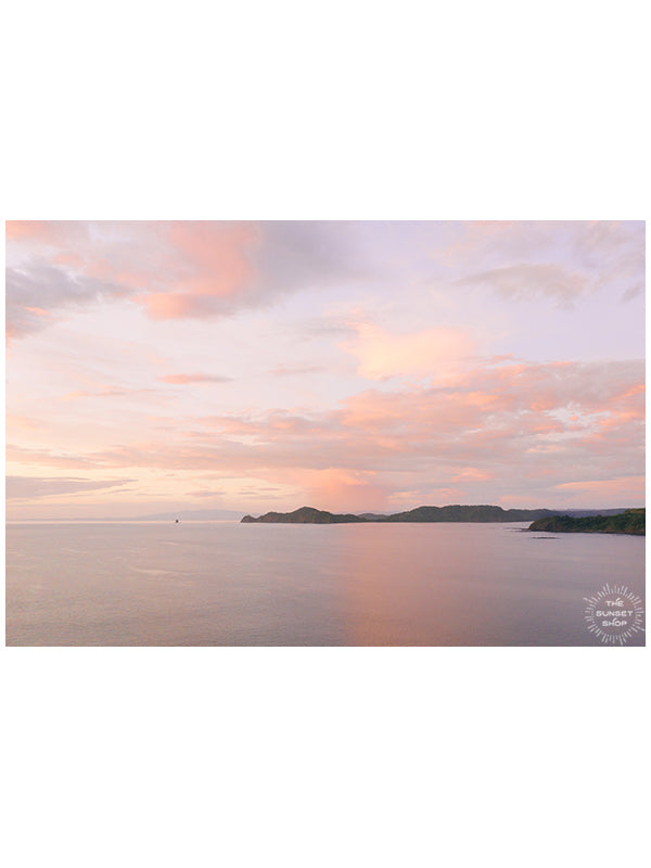 There is freedom waiting for you, on the breezes of the sky, and you ask, "What if I fall?" Oh but my darling, what if you fly? Aerial photo of a pastel sunset casting a pink glow over the ocean in Playa Hermosa Costa Rica.