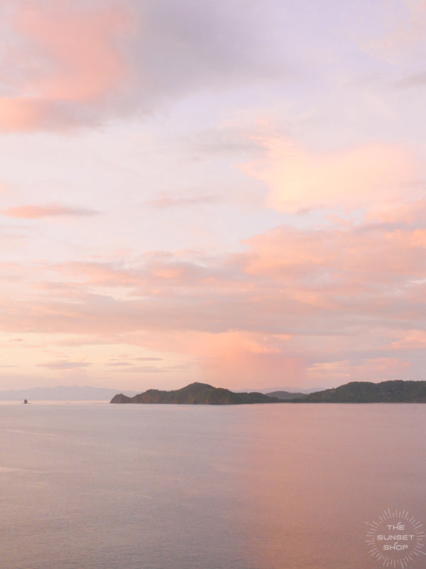 There is freedom waiting for you, on the breezes of the sky, and you ask, "What if I fall?" Oh but my darling, what if you fly? Aerial photo of a pastel sunset casting a pink glow over the ocean in Playa Hermosa Costa Rica.