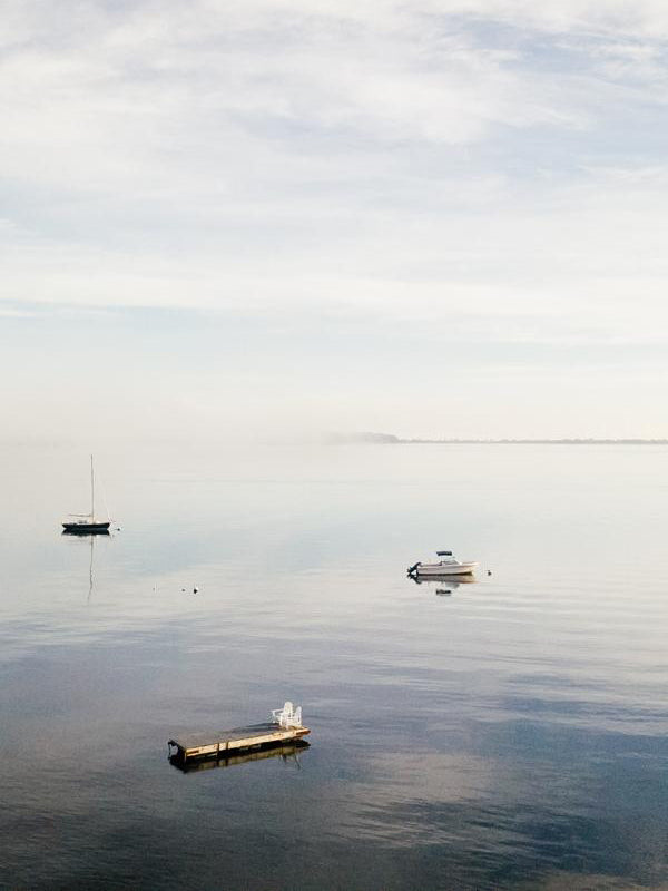 Morning Magic. Fog rolling in over Huntington Bay on the North Shore of Long Island. Aerial image of boats anchored in the bay during a calm, foggy early morning in Huntington, NY. Photographed by Kristen M. Brown, Samba to the Sea.