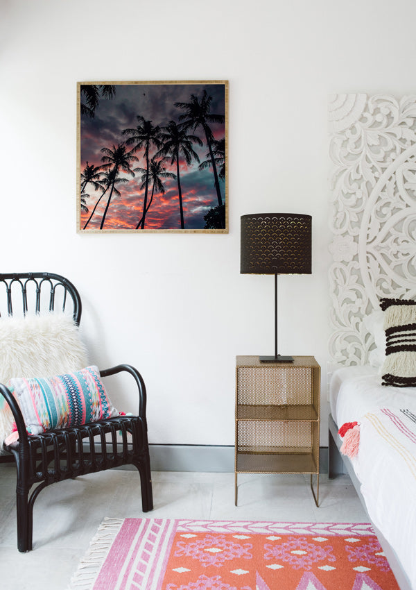Boho chic bedroom with framed sunset beach print. Palm tree sunset sky in Costa Rica. Black rattan chair, Urban Outfitters rug, Target home decor, . Photographed by Samba to the Sea for The Sunset Shop.