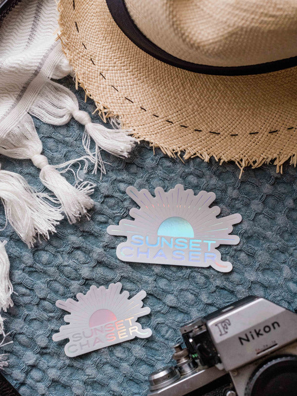 Do you love to chase sunsets? Is sunset your favorite color? Then this Sunset Chaser holographic sticker has your name on it! Printed with a holographic sheen, you'll be mesmerized by how this sticker changes colors as it catches and reflects light -- just like breathtaking sunset! From shades of ocean turquoise to pink sunset, this Sunset Chaser sticker is your little slice of sunset magic. By Samba to the Sea at The Sunset Shop.