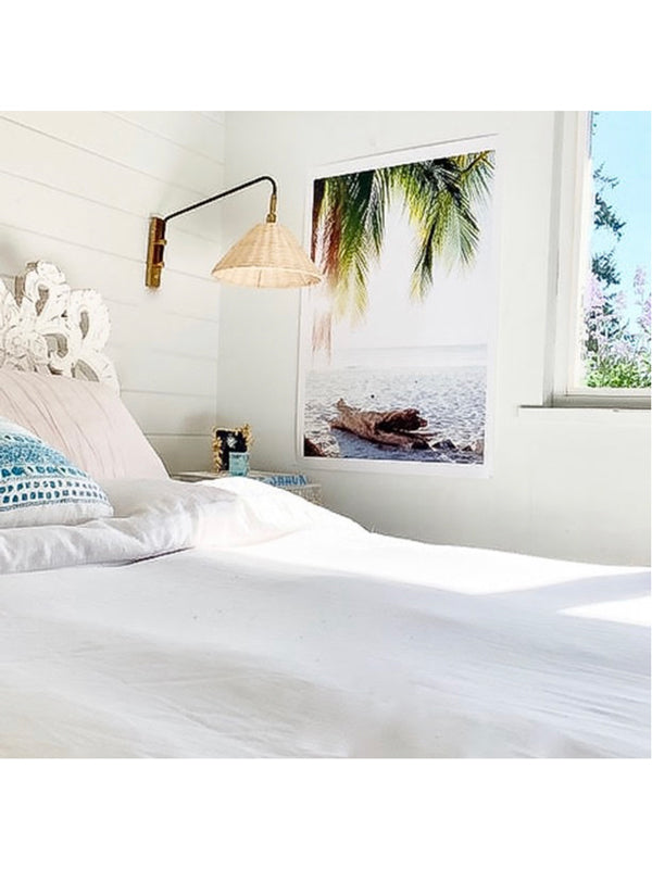 White coastal bedroom with tropical palm tree photo print. Surf shack and beach bungalow vibes. "Via Paradise" beach print by Kristen M. Brown of Samba to the Sea for The Sunset Shop.