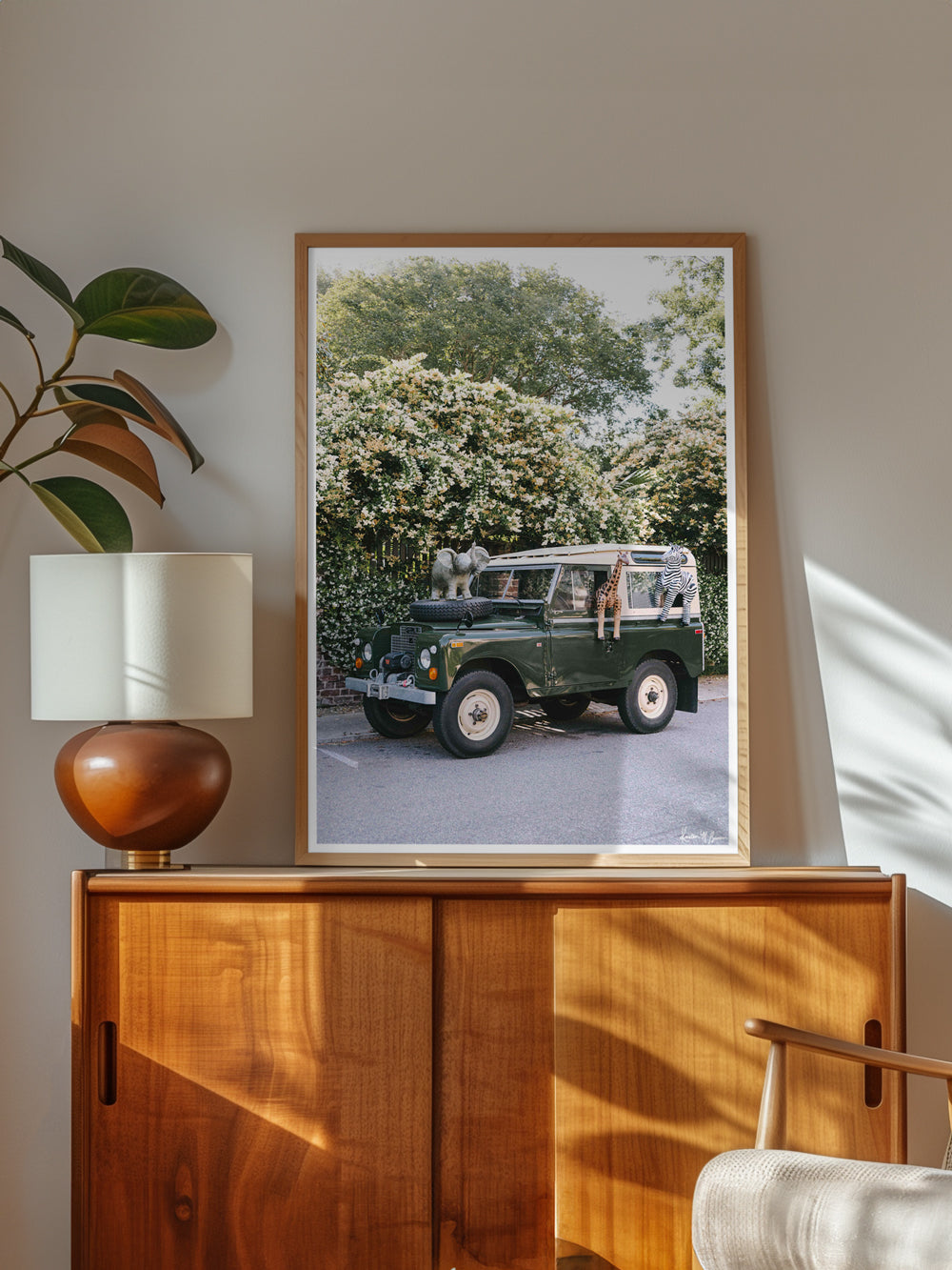 Step on into a whimsical world of adventure with "Africa Awaits"! Featuring a classic green Land Rover Series three playfully adorned with blow up safari animals backdropped by fragrantly blooming Star Jasmine, this fine art photograph celebrates the spirit of exploration and childhood wonder. Photo print by Kristen M. Brown of Samba to the Sea for The Sunset Shop.