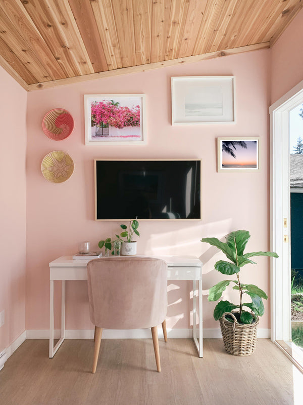 Costa Rica photo prints "Bloom Baby Bloom" and "Tropical Sol" from The Sunset Shop hanging in a feminine, beachy backyard office. Beach gallery wall art, light pink walls, fiddle leaf fig, Samsung Art tv, velvet desk chair for work from home office.