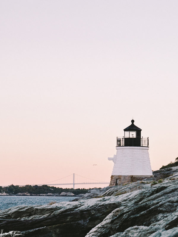 "Castle Hill en Rosé" photo print of the Castle Hill lighthouse in Newport, Rhode Island with a dreamy pastel pink sunrise sky and the Clairborne Pell Newport Bridge in the background. Photographed by Kristen M. Brown of Samba to the Sea for The Sunset Shop.