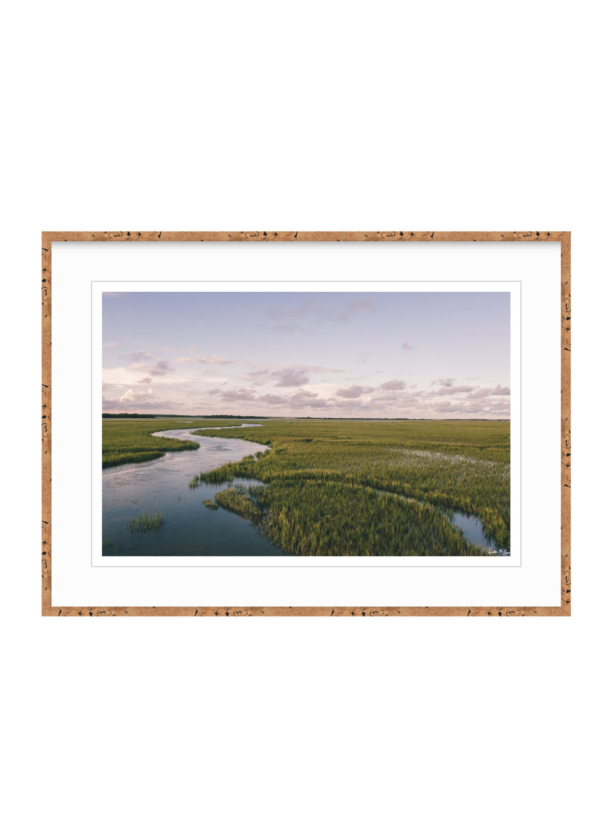 Framed landscape art print featuring a winding river through green marshlands under a pale sky, presented in a cork frame with a white mat on a white background. A scenic landscape photograph of a winding river flowing through a vast green marsh under a pale blue and pink sky. "Creek Serenade" photo print of golden hour over the a marsh wandering creek during high tide in Charleston, SC. Photo by Kristen M. Brown of Samba to the Sea for The Sunset Shop.