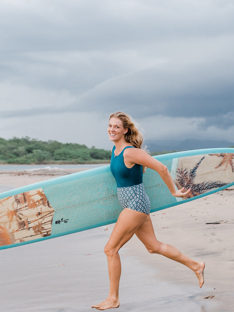 Image of photographer Kristen M. Brown running into the ocean with her surfboard in Costa Rica.