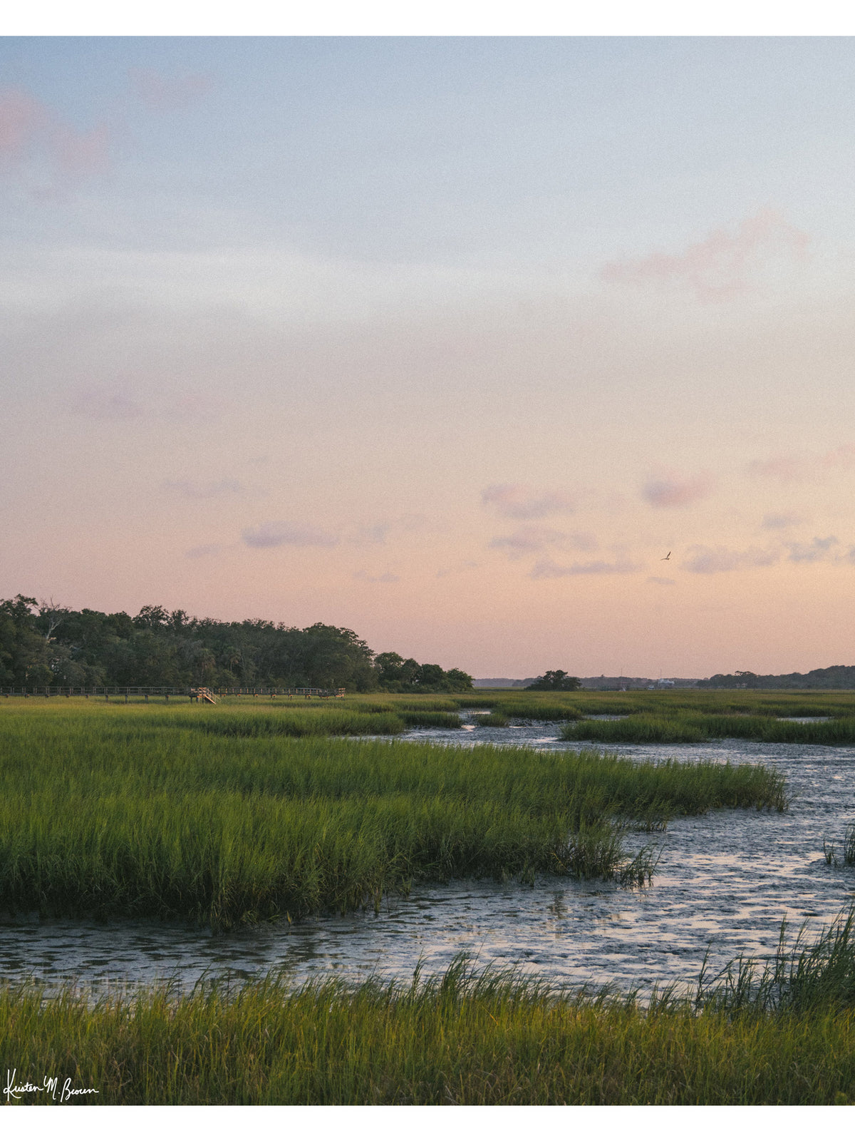 Scenic landscape photograph of pastel sunset over the low tide marsh. When the day settles into twilight, the marsh softens into a painterly blend of pastel skies, swaying marsh grass, and the gentle ebb of the tide. Photo print by Kristen M. Brown of Samba to the Sea for The Sunset Shop.