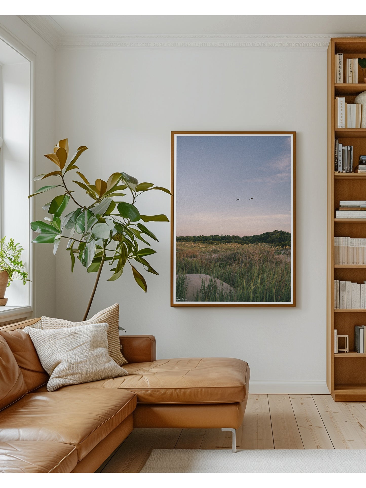 Framed Sullivan’s Island in Charleston, SC “Morning Flight” photo print. Across A wild expanse of dune grass and golden sea oats, two pelicans soar in effortless tandem against the gentle palette of dawn. In the background, lush maritime forest trees frame the horizon, while the soft, morning light washes over the dunes in calm, subtle tones. By Kristen M. Brown.