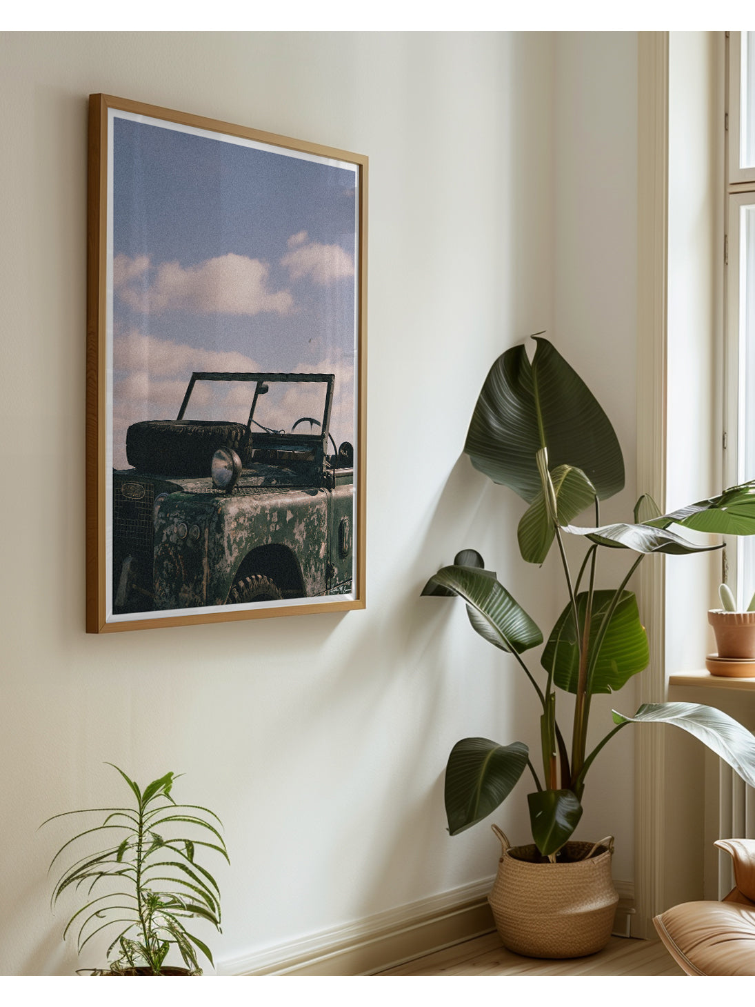 A framed vintage Land Rover wall art print displayed in a styled room corner with potted plants and a window. The raw, authentic character of this vintage 1963 Land Rover Series truck, with its iconic hood-mounted spare tire, open-top frame, and soft patina earned through years of adventure, "Patina" embodies the spirit of adventure.  Bring a touch of rugged soul, vintage heritage, and timeless  wanderlust into your space with "Patina", a print that turns rustic wear into pure artistry. 