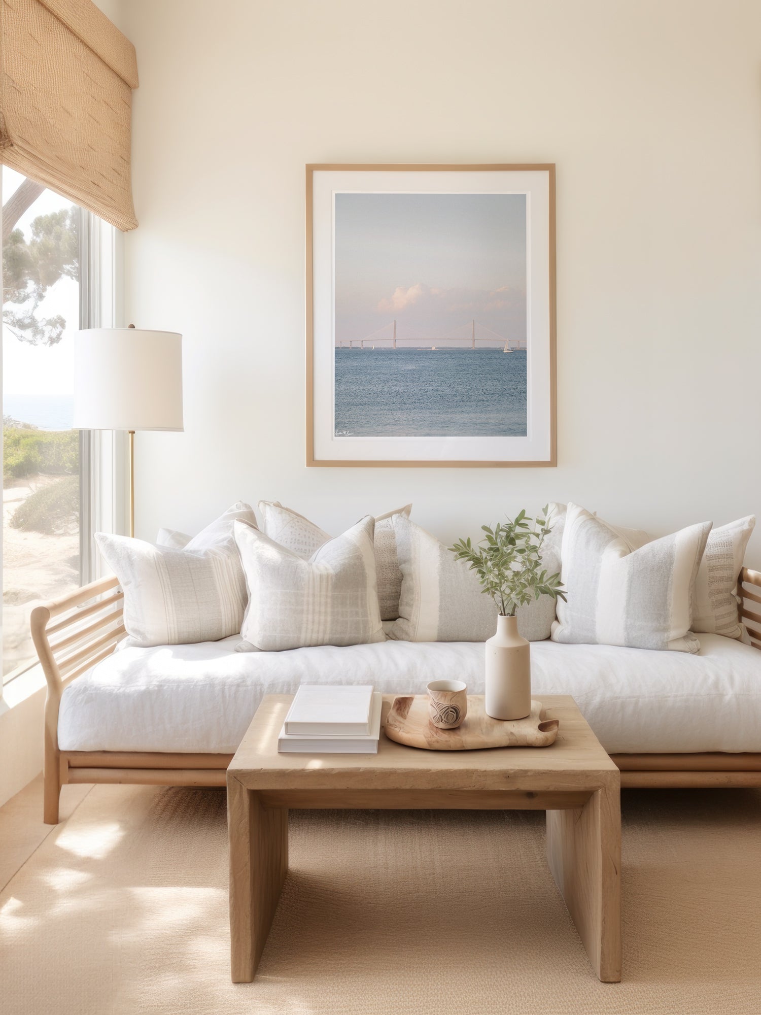 Photography print of sailboats sailing in Charleston Harbor with Ravenel Bridge on a gorgeous afternoon under blue skies. Print hanging in a coastal living room above couch. “Saltwater Charmed” photographed by Kristen M. Brown, Samba to the Sea.
