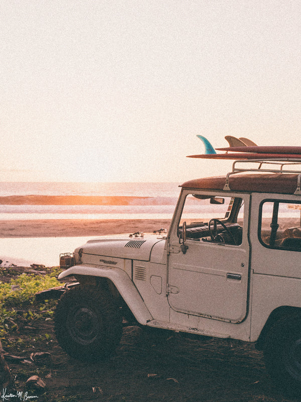 &quot;Seek and You Will Find&quot; photo print of vintage Toyota FJ40 Land Cruiser racked up with surfboards parked at the beach in Costa Rica as the waves peel and the sun kissing the horizon turns everything golden. Photographed by Costa Rica photographer Kristen M. Brown of Samba to the Sea for The Sunset Shop.