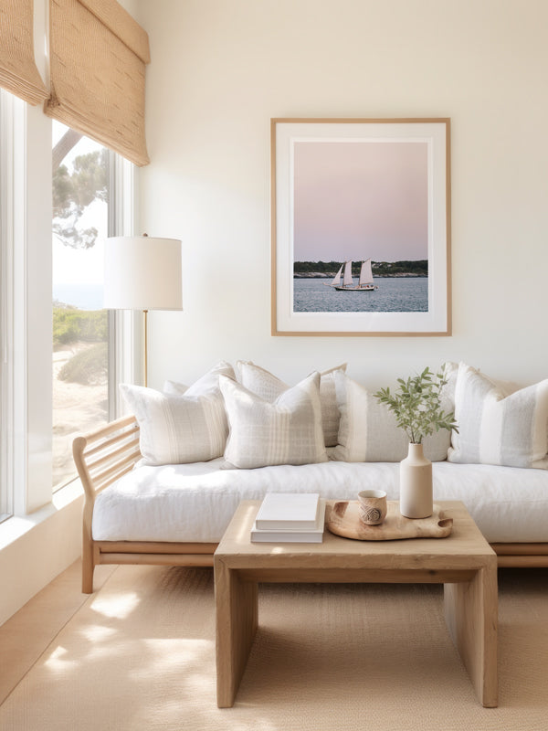 Set Sail at Sunrise" photo print of schooner sailboat sailing in Newport, Rhode Island during a pastel pink sunrise hanging in a serene, coastal living room.Welcome back to your coastal New England sailing daydream, all from the comfort of your home...wherever home may be with "Set Sail at Sunrise".  Photographed by Kristen M. Brown of Samba to the Sea for The Sunset Shop.