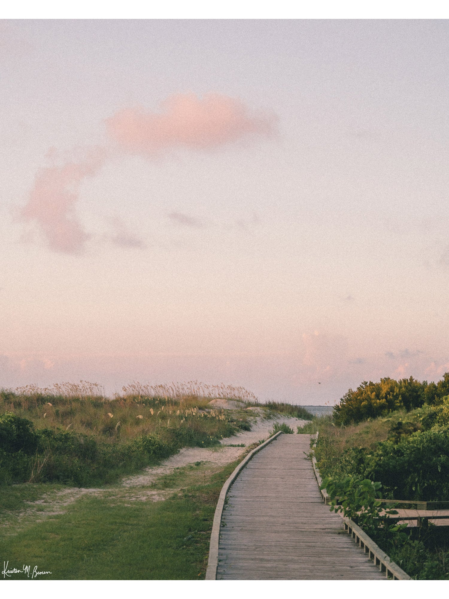 Before the world wakes up and when the shoreline belongs entirely to you, a pastel cloud drifts through a sky painted in soft blushes of pink, peach, and muted lavender, catching the very first light of dawn through the beach dunes and path boardwalk Station on Sullivan’s Island, SC. Bring home that feeling with "Station Sunrise". Photo print by Kristen M. Brown of Samba to the Sea for The Sunset Shop.