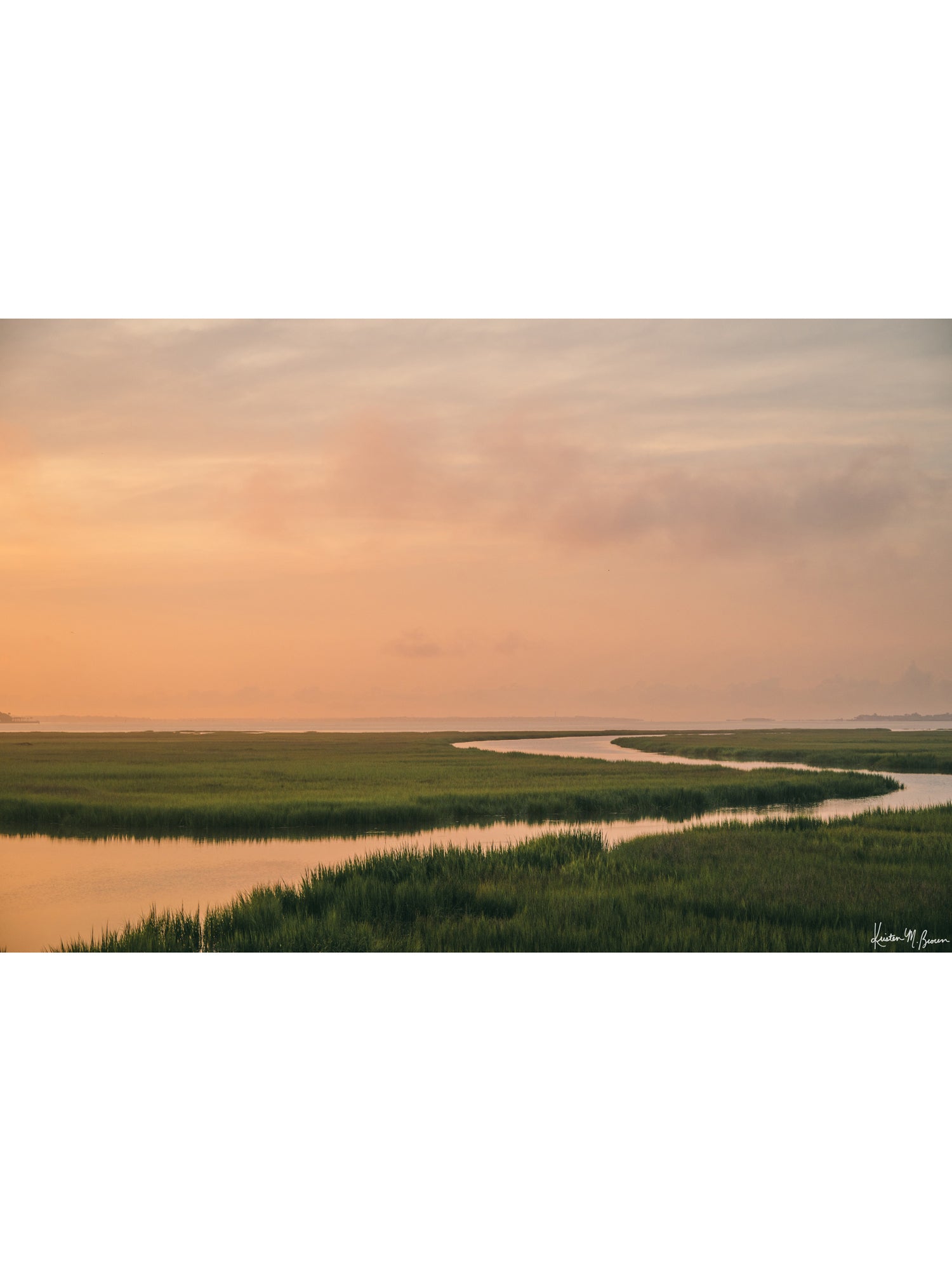 A scenic landscape photograph of a winding creek flowing through the marsh during sunrise, with the soft peach and pink clouds in the sky above and reflecting in the waters. "Tidal Glow" fine art photography print photographed by Kristen M. Brown, Samba to the Sea.