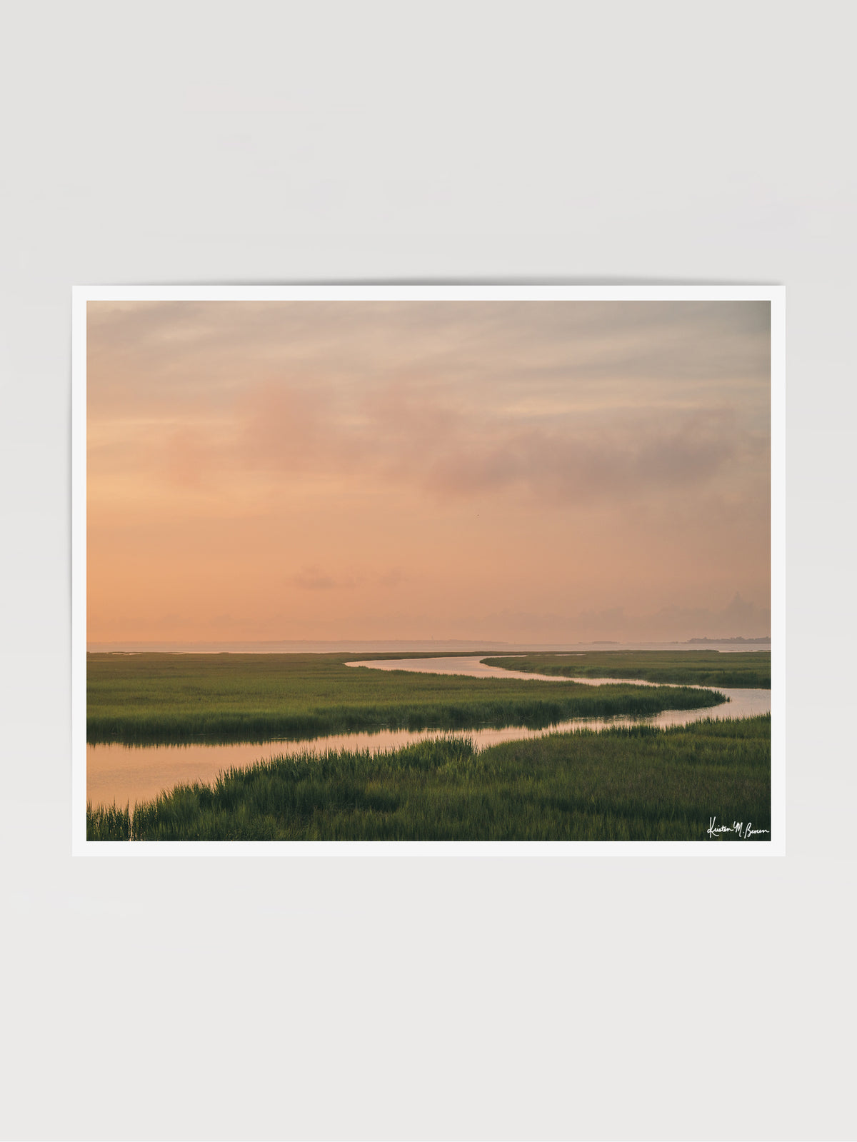 A scenic landscape photograph print of a winding creek flowing through the marsh during sunrise, with the soft peach and pink clouds in the sky above and reflecting in the waters. "Tidal Glow" fine art photography print photographed by Kristen M. Brown, Samba to the Sea.