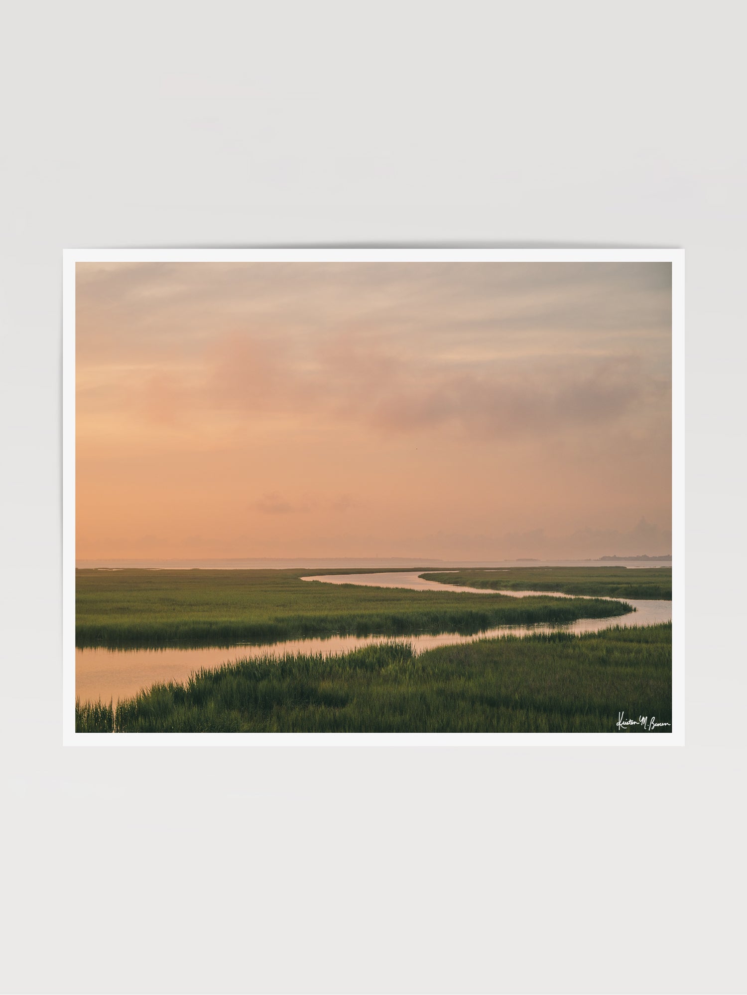 A scenic landscape photograph print of a winding creek flowing through the marsh during sunrise, with the soft peach and pink clouds in the sky above and reflecting in the waters. "Tidal Glow" fine art photography print photographed by Kristen M. Brown, Samba to the Sea.