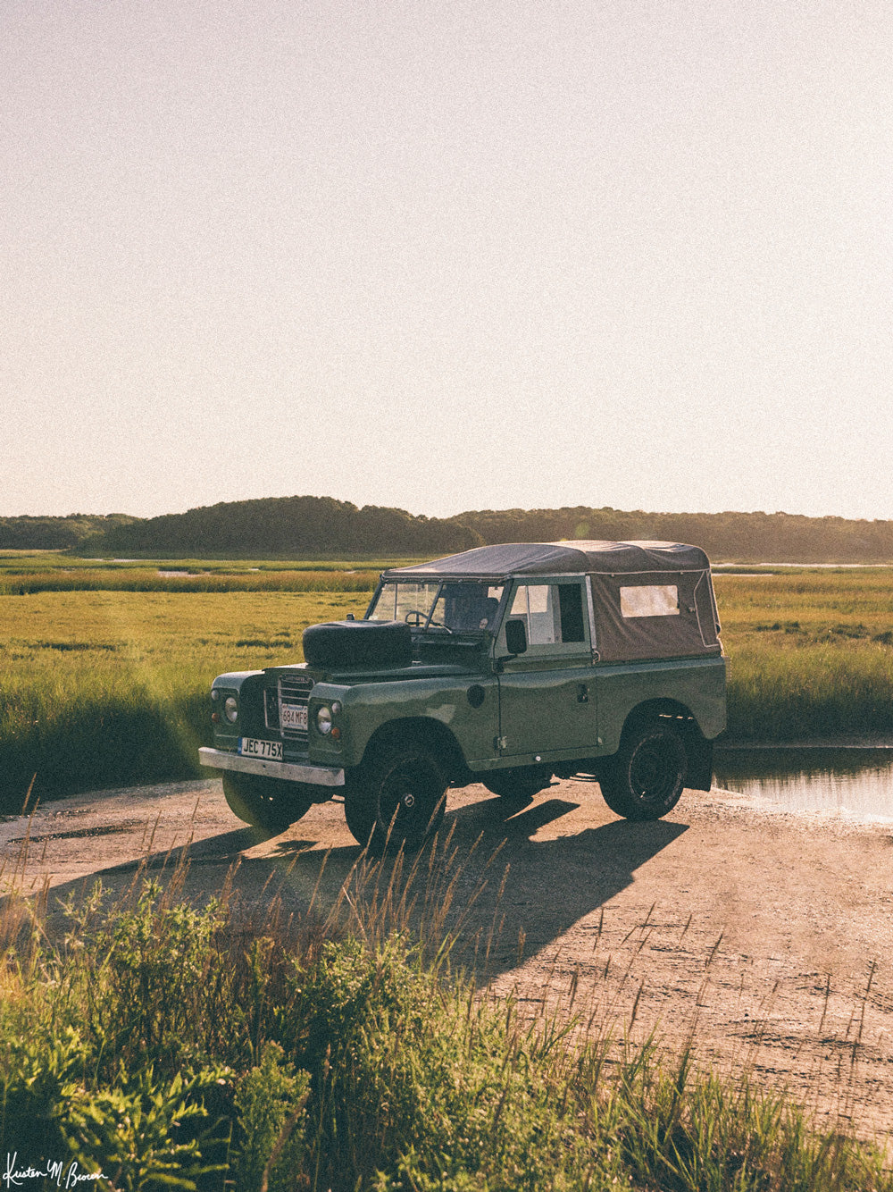 There&#39;s nothing like knowing that a day of adventure with your Rover is on tap to get you out of bed in the morning! Especially when that adventure has you exploring Cape Cod&#39;s beautiful beaches on a pristine blue sky day. So what are you waiting for? Hop on into this Series III that&#39;s glowing in the early morning light and get going! Photo print by Kristen M. Brown of Samba to the Sea for The Sunset Shop.