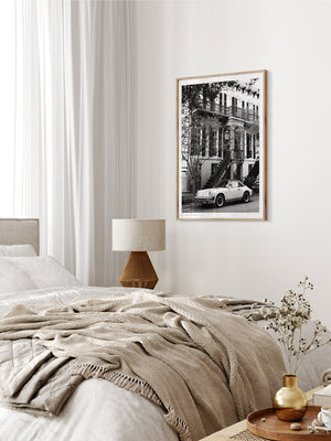 Porsche 911 parked in Savannah Georgia black and white wall art in neutral bedroom with caning furniture. "911 Porsche in 912 Savannah" B&W photo print by Kristen M. Brown of Samba to the Sea for The Sunset Shop.