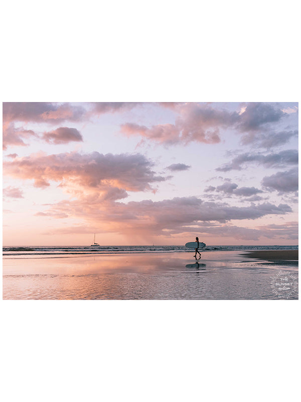 Angel del Mar - Sea Angel sunset surfer girl print by Samba to the Sea at The Sunset Shop. Photo of a female surfer walking on the beach during a pastel pink sunset in Tamarindo, Costa Rica.