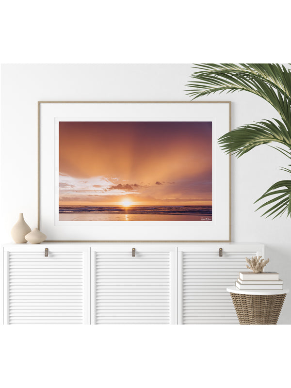 White tropical coastal living room with gorgeous sunset photography print. Tamarindo Costa Rica breathtaking sunset with the suns rays breaking through the clouds in Costa Rica. Photo by Kristen M. Brown, Samba to the Sea for The Sunset Shop.