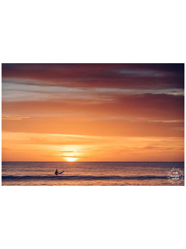 Surfer watching a golden orange sunset in the ocean in Tamarindo Costa Rica. Photographed by Kristen M. Brown, Samba to the Sea.