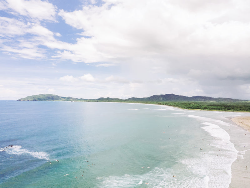 Aerial image of the the beach in Tamarindo Costa Rica. Drone image of turquoise ocean water and surfers. Aerial beach print by Samba to the Sea at The Sunset Shop.