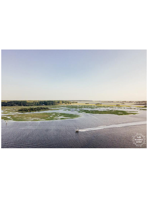 Lowcountry Living. Boat cruising down the river in Savannah, Georgia on Skidaway Island. Photographed by Kristen M. Brown, Samba to the Sea.