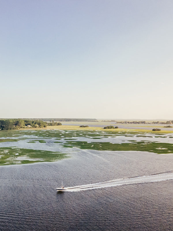 Lowcountry Living. Boat cruising down the river in Savannah, Georgia on Skidaway Island. Photographed by Kristen M. Brown, Samba to the Sea.
