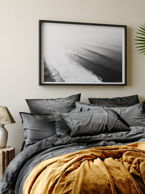 Moody Spanish coastal bedroom with black and white aerial wave photo print hanging above bed. "Hermosa Dreaming" black and white aerial photo print of beautiful breaking wave in Costa Rica by Samba to the Sea.