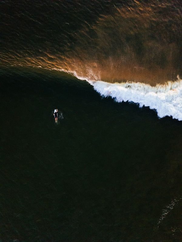 Aerial surfer print by Samba to the Sea at The Sunset Shop. Image is an aerial photo of surfer paddling out to surf in Tamarindo, Costa Rica.