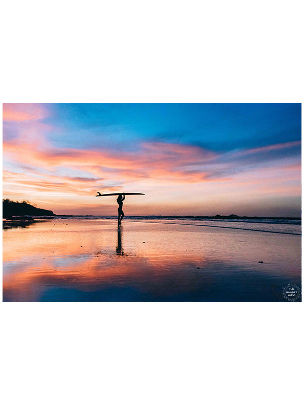 Pura Amor / Pure Love sunset female surfer print by Samba to the Sea at The Sunset Shop. Photo of a female surfer on the beach during a breathtaking sunset in Tamarindo, Costa Rica.