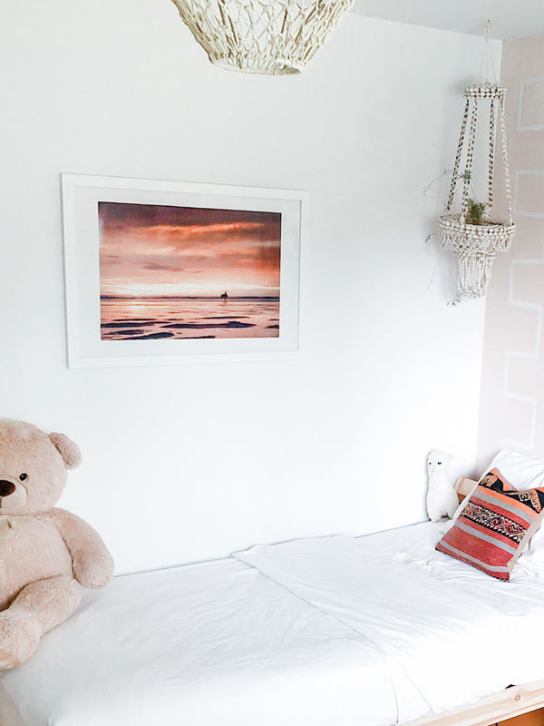 She's Magic sunset surfer print by Samba to the Sea at The Sunset Shop. Photo of a female surfer walking on the beach during a pastel pink sunset in Tamarindo, Costa Rica.