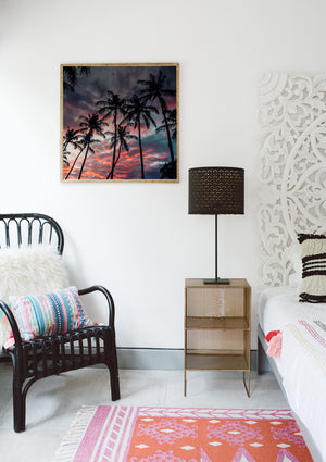 Boho chic bedroom with framed sunset beach print. Palm tree sunset sky in Costa Rica. Black rattan chair, Urban Outfitters rug, Target home decor, . Photographed by Samba to the Sea for The Sunset Shop.