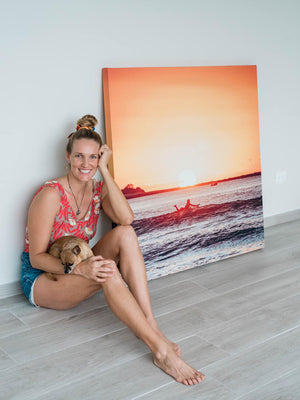 Costa Rica photographer Kristen M. Brown sitting next to her surfer print "The Girl + The Water". Sunset surfer print by Samba to the Sea at The Sunset Shop.