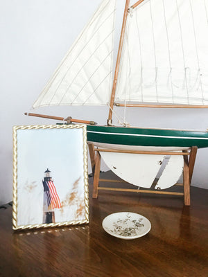 American flag hanging on the Tybee Island Lighthouse. Nautical home decor with model sailboat. "Sweet Liberty" available at The Sunset Shop by Kristen M. Brown of Samba to the Sea.