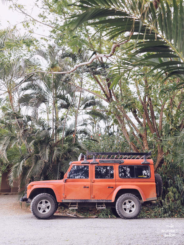 Because life is all about the magic in the detours and the beauty of taking time to explore bumpy, back road dirt roads in tropical paradise with a vibrant red Land Rover Defender just like this. "Tropical Sleigh" photographed by Kristen M. Brown, Samba to the Sea for The Sunset Shop.