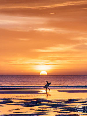 Surfer walking on the beach during an orange sunset in Costa Rica. Walking On Sunshine sunset photo by Samba to the Sea at The Sunset Shop.